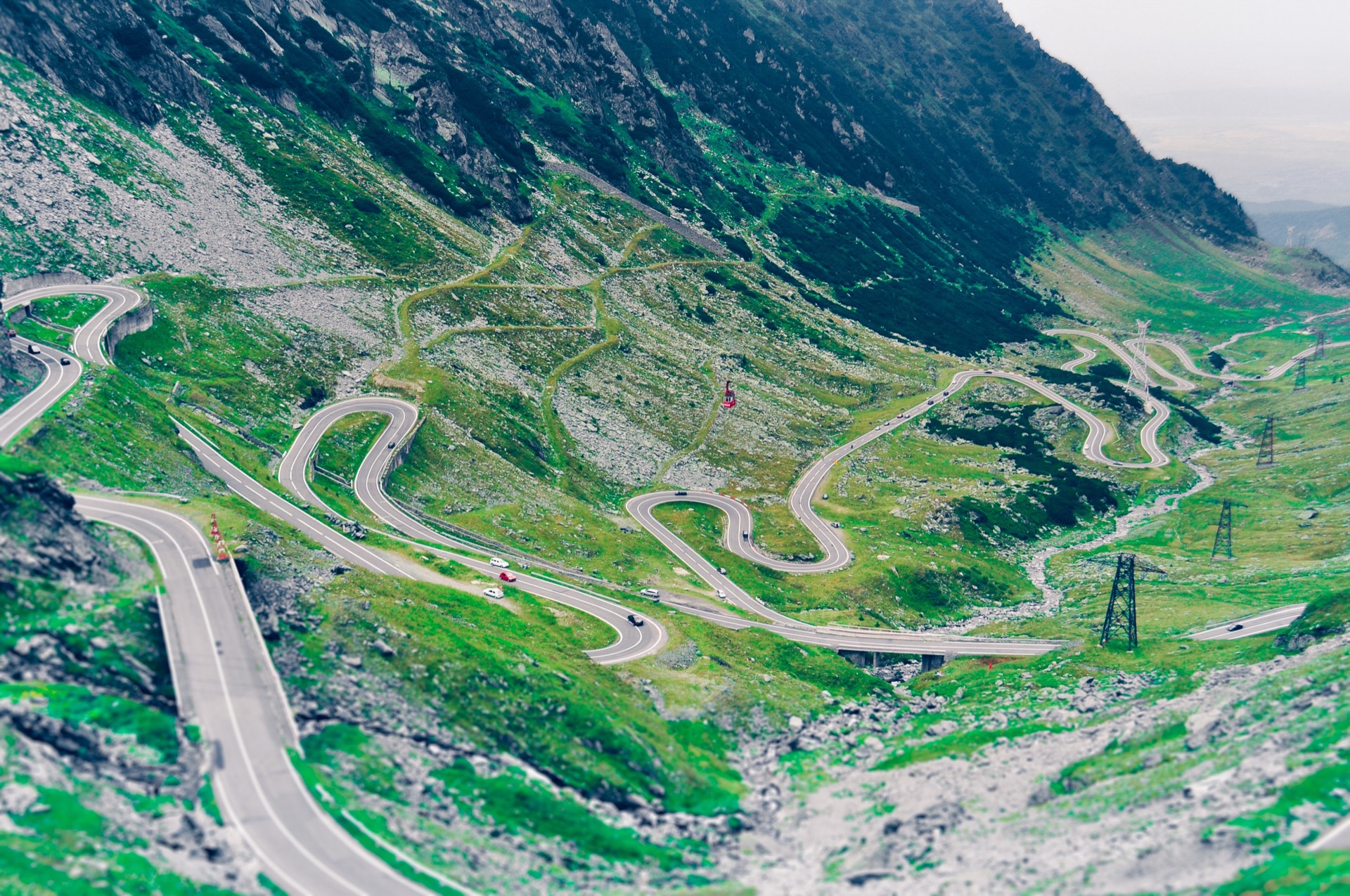 Stacked hairpin bends of the Transfagarasan mountain road winding up a green valley